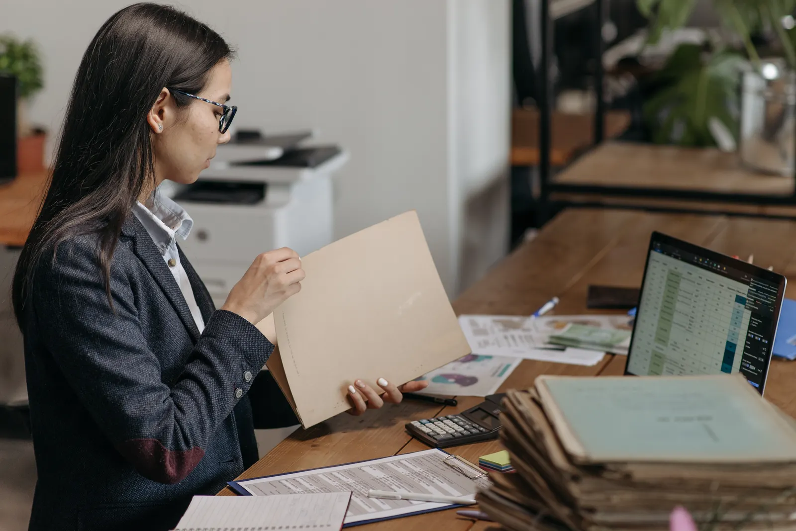Accountant reviewing client folders and documents at a laptop, representing custom AI bookkeeping integrated into a firm's existing workflow